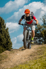 Man on a fat bike storming or riding downhill. Professional biker on a trail with a fat bike.