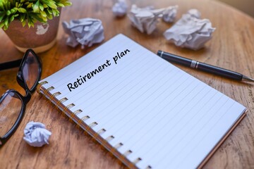 Message on retirement plan written on the notebook with eyeglasses, crumpled paper, and a ballpoint...