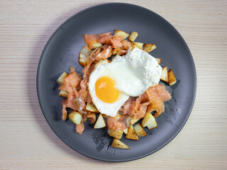 A plate of smoked salmon, potato hash, and fried egg.