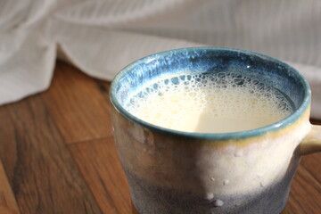 木目の机の上に置いてあるみかんとカップ