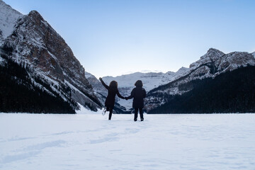Lake Louise, Canada - december 2020 : Back view of a couple standing in the snow on the frozen lake 
