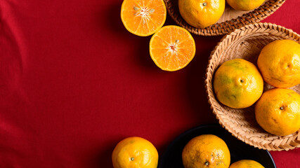 Tangerine orange fruit in bamboo basket on red background, Top view