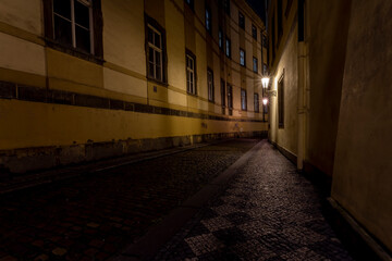 .lit street lights and a cobbled street with cobblestones in the center of Prague at night