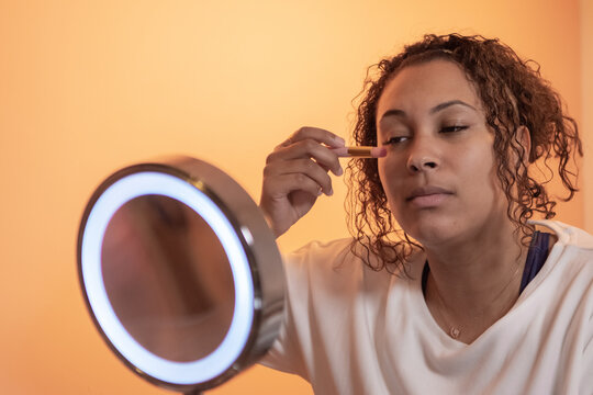 ethnic woman using beauty and make up products in front the mirror,