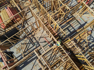 Aerial view of a new building being framed by carpenters. Worker builder working on building structure on construction site.