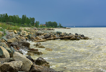 Shore of the Ob sea. Big stones on the Bank of the Novosibirsk reservoir, waves on the water
