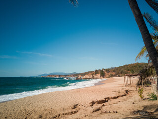 Playa, mar, arena, gente, rocas y una enramada