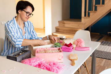 Woman preparing gift boxes with beauty and bath products of body care for Mothers Day