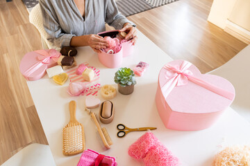 Woman preparing gift box set with handmade natural body care products and bath supplies