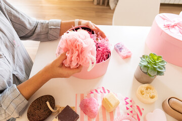 Woman preparing gift box set with handmade natural body care products and bath supplies