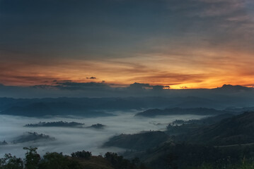 Obraz premium Fluffy fog stream is covering a valley with colorful twilight sky in a morning
