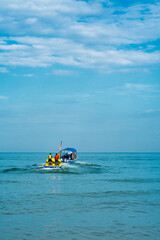 Boat pulling floating water raft and banana boat in the sea.