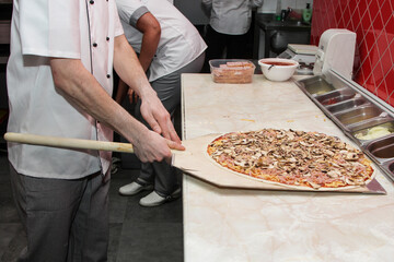 The process of making pizza. Hands of chef baker making pizza at cafe kitchen