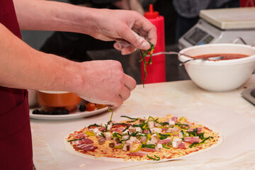 The process of making pizza. Hands of chef baker making pizza at cafe kitchen