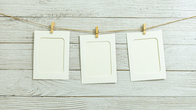 Paper photo frame on white wooden wall background with copy space