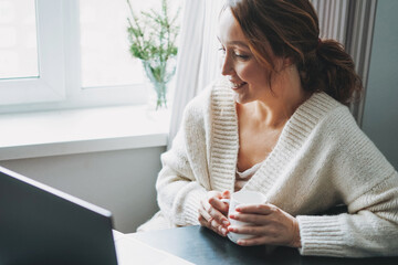 Attractive friendly smiling brunette woman middle age using laptop at home cozy vibes cold season
