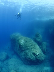 scuba diver underwater with rocks discovering reefs ocean scenery human