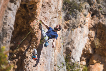 Obraz premium Climber overcomes a difficult climbing route on a natural terrain.