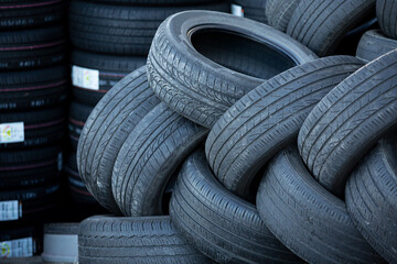 Pile of used tires on a background of new tires