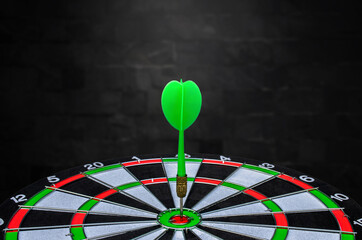 Planning new business target and goals, Green dart arrow hitting in the target center of dartboard...