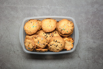 Homemade crunchy chocolate cookies chips on a plastic container on a grey background