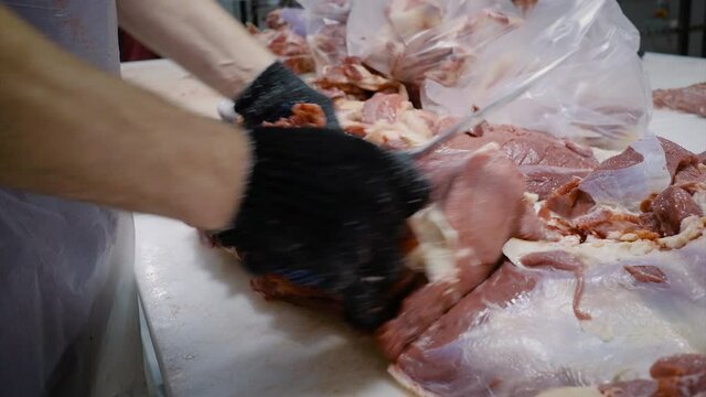 The butcher cuts the meat with a knife. Cuts off pieces of meat. Close-up