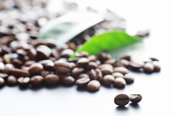 Fototapeta premium Bag of coffee. Coffee beans roasted on the table. Coffee beans with green leaves for cooking.