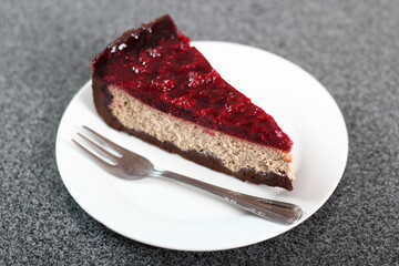 Cheesecake with chocolate crumb base topped with raspberry jelly