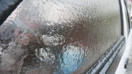 Frozen car glass with ice and snow. Drives door. Consequences of rain and frost