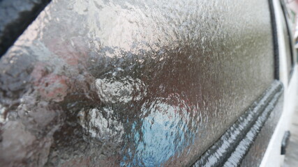 Fototapeta premium Frozen car glass with ice and snow. Drives door. Consequences of rain and frost