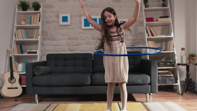 Little girl exercising hula hoop at home.The girl happily shakes the hula hoop at home and enjoys exercising with a smile.