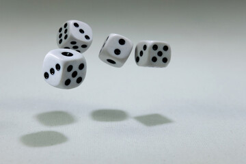  White playing dice cubes in motion on the white canvass surface, selective focus