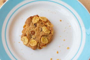 Cereal cookie in plate on wooden table. Crunchy fresh baked cookie with crumbs.