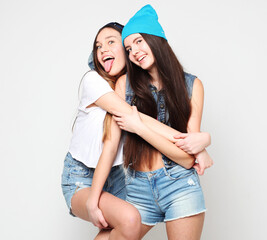 Two fashion laughing female friends hugging and having fun