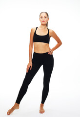 Portrait of beautiful young woman wearing sportswear working out in studio. Fit sporty girl doing yoga. Full length.