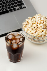 Watching movie on laptop with popcorn and iced soda drink