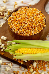 Corn cob, corn seeds and popcorn in composition on black background