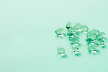 beautiful green luminous gelatin capsules pills vitamins close-up on a green background, place for text 