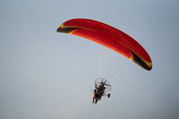 A wide angle view of a paraglider flying high in the sky against a blue background. Space for copy...