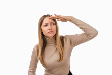 Portrait of a curious blond girl looking far away with hand at her forehead, trying to see something far away