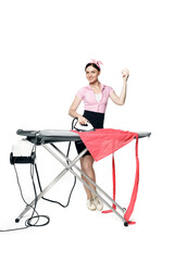 Fototapeta premium Snaps fingers. A beautiful girl dressed in pin-up style is ironing clothes looks at the camera and smiles isolated on a white background.