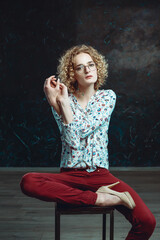 A young blond man androgyne in the image of an attractive woman dressed in a floral shirt, posing...