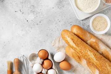 Fototapeta na wymiar Baguette round bread. French baguette bread is surrounded by baking ingredients. Bread close-up. Eggs, salt, flour, seeds on the kitchen table. Top view with copyspace