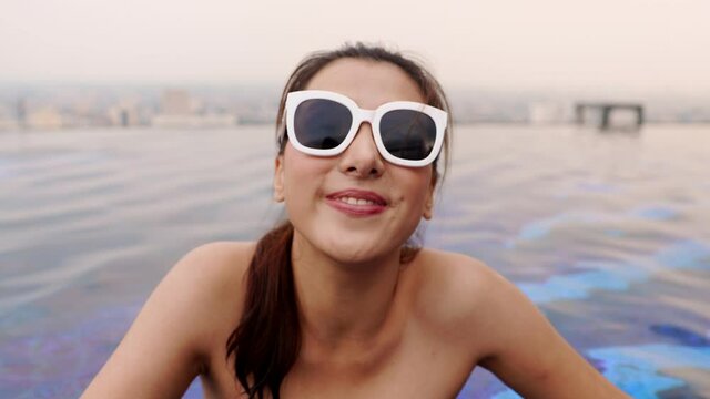 Asian young woman relaxing in swimming pool at luxury hotel spa enjoying beautiful sunset . Close up  Female Enjoying Summer Travel .vacation woman in bikini .