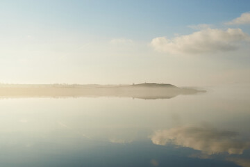 mist laying over the calm water on a silent morning at Flyndersoe lake in Denmark