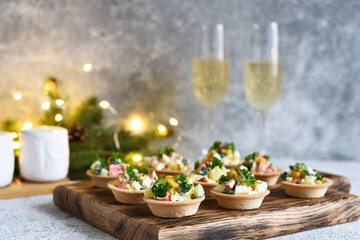 Tartlets with crab sticks and corn and champagne in a glass on the New Year's table.