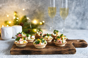 Fototapeta na wymiar Tartlets with crab sticks and corn and champagne in a glass on the New Year's table.