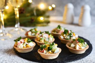 Tartlets with crab sticks and corn and champagne in a glass on the New Year's table.