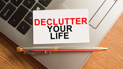 Notepad with the text DECLUTTER YOUR LIFE is on the laptop keyboard. Minimal work space. Business concept.