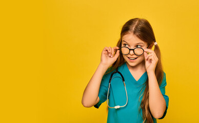 Girl wearing in a blue doctor uniform and a stethoscope playing the medical profession, and shows on her face emotion of surprise, taking off glasses